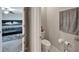 Modern half bathroom featuring white fixtures, gray walls, and entry view to bedroom at 16685 Parker River St, Wimauma, FL 33598