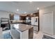 Well-lit kitchen with dark cabinets, stainless steel appliances, a center island, and white tile flooring at 16685 Parker River St, Wimauma, FL 33598