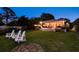 Backyard view featuring a patio, lush lawn, white chairs, and a glimpse of a relaxing hot tub at 1748 Sunset Dr, Clearwater, FL 33755
