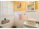 A bathroom with a toilet, sink, mirror, painting, small storage basket and a window with closed white shutters at 1748 Sunset Dr, Clearwater, FL 33755