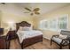A bedroom with a wooden bed, ceiling fan, white shutters, hardwood floors and a small chair at 1748 Sunset Dr, Clearwater, FL 33755