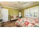 A bedroom with a wooden bed, beige bench with pillows, green walls, hardwood floors and a door at 1748 Sunset Dr, Clearwater, FL 33755