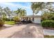 Home's front exterior features a well-manicured lawn, lush landscaping, a boat trailer and a brick driveway at 1748 Sunset Dr, Clearwater, FL 33755