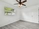Bright bedroom with natural light from the window with gray wood floors and ceiling fan at 2401 Havana Dr, Clearwater, FL 33764