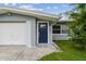 Close up view of the front of the house, with a blue door, garage, and green lawn at 2401 Havana Dr, Clearwater, FL 33764
