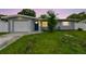 Charming single-story home at sunset featuring a lush front yard and attached garage at 2401 Havana Dr, Clearwater, FL 33764