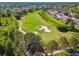 An aerial view of a neighborhood bordering a golf course with mature trees and lush green landscaping at 3148 Sago Point Ct, Land O Lakes, FL 34639