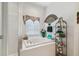 A soaking tub with a tile surround, window, and glass-enclosed shower in the main bathroom at 3148 Sago Point Ct, Land O Lakes, FL 34639