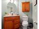 Well-lit half bathroom features wood cabinet vanity, toilet, and round mirror at 3434 Tarbolton Way, Land O Lakes, FL 34638