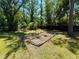 A backyard featuring concrete planters sits amongst a spacious green lawn and surrounded by lush trees at 4310 Lithia Pinecrest Rd, Valrico, FL 33596