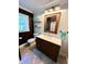 Well-lit bathroom featuring dark vanity, white countertop, rustic mirror, and a toilet with overhead shelving at 4310 Lithia Pinecrest Rd, Valrico, FL 33596