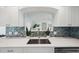 Bright kitchen sink features blue tiled backsplash, stainless faucet, and quartz countertops at 504 69Th St, Holmes Beach, FL 34217
