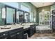 Elegant bathroom featuring double sinks, modern lighting, and a soaking tub at 5269 Karlsburg Pl, Palm Harbor, FL 34685
