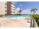 Community pool with lounge chairs, mature landscaping, and a building view at 5575 Gulf Blvd # 421, St Pete Beach, FL 33706