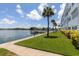 Scenic waterfront view with a private dock, lush green lawn, palm trees, and a clear blue sky at 5575 Gulf Blvd # 421, St Pete Beach, FL 33706