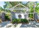 Stone wall at community entrance with white wooden pergola-style roof and manicured landscaping at 5807 Thoreau Pl, Lithia, FL 33547