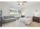 Bright bedroom with a ceiling fan, comfortable sofa, and a large window with outdoor views at 5833 Grand Sonata Ave, Lutz, FL 33558