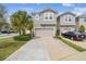 Two-story gray home features a two-car garage, well-manicured lawn, and is tastefully landscaped with lovely palms at 5833 Grand Sonata Ave, Lutz, FL 33558