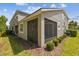 A view of the exterior of a home with a screened-in porch and landscaped yard with mulch and green grass at 5833 Grand Sonata Ave, Lutz, FL 33558