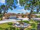 Lovely single-story home with a circle driveway and fountain on a manicured lawn beneath mature shade trees at 6732 Udell Ln, Hudson, FL 34667