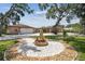 Charming home with a circular brick paver design and a decorative fountain surrounded by colorful flowers at 6732 Udell Ln, Hudson, FL 34667