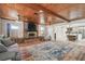 Open-concept living area with a brick fireplace, wood-paneled ceiling, and seamless flow into the dining and kitchen spaces at 6732 Udell Ln, Hudson, FL 34667