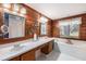 Elegant bathroom featuring a soaking tub, double sinks, and wood paneled walls at 7157 Quail Hollow Blvd, Wesley Chapel, FL 33544