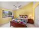 Sunny bedroom with bright yellow walls, ceiling fan, and a large window at 7157 Quail Hollow Blvd, Wesley Chapel, FL 33544