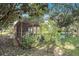 A spacious chicken coop with mesh siding, wooden frame, and lush greenery in a tranquil backyard setting at 7157 Quail Hollow Blvd, Wesley Chapel, FL 33544
