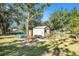 Backyard shed with lush greenery, picnic table, and equipment against a backdrop of mature trees at 7157 Quail Hollow Blvd, Wesley Chapel, FL 33544