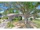 Single-story home featuring a covered driveway, lush landscaping and a large tree at 7703 W Hiawatha St, Tampa, FL 33615