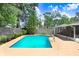 Sparkling pool with a concrete deck, set amidst a beautifully landscaped backyard with trees at 7703 W Hiawatha St, Tampa, FL 33615