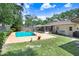 Inviting backyard pool with a concrete deck, complemented by lush green landscaping and mature trees at 7703 W Hiawatha St, Tampa, FL 33615