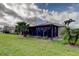 Home exterior featuring a screened-in lanai with lush landscaping in the backyard at 10103 Old Tampa Bay Dr, San Antonio, FL 33576