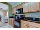 Cozy kitchen featuring wooden cabinets, black appliances, and a view to the living room at 10103 Old Tampa Bay Dr, San Antonio, FL 33576