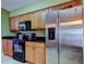 Charming kitchen featuring wooden cabinets, black countertops, and stainless steel refrigerator at 10103 Old Tampa Bay Dr, San Antonio, FL 33576