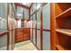 Walk-in closet with wood cabinetry, mirrored vanity, and ample storage space for clothing and accessories at 1058 Roundstone Pl, Palm Harbor, FL 34683