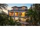 Rear of a grand home featuring multiple balconies, large windows, and lush tropical landscaping surrounding the pool at 1058 Roundstone Pl, Palm Harbor, FL 34683