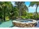 The pristine stone hot tub is surrounded by lush landscaping that provides ultimate privacy at 1058 Roundstone Pl, Palm Harbor, FL 34683
