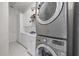 Bright laundry room with stacked washer and dryer and white cabinets at 1058 Roundstone Pl, Palm Harbor, FL 34683