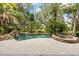 Freeform pool surrounded by lush tropical landscaping, a stone waterfall feature, and an adjacent stone hot tub at 1058 Roundstone Pl, Palm Harbor, FL 34683