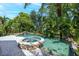 Beautiful backyard pool and stone hot tub surrounded by tropical landscaping and pavers at 1058 Roundstone Pl, Palm Harbor, FL 34683