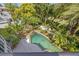 Aerial view of a tropical backyard paradise, boasting a private pool with waterfall feature surrounded by lush landscaping at 1058 Roundstone Pl, Palm Harbor, FL 34683