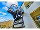 Exterior spiral staircase leading to a second-story balcony on a light-colored stucco home against a sunny, blue sky at 1058 Roundstone Pl, Palm Harbor, FL 34683