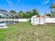 Fenced backyard features a screened pool enclosure, lush green grass, and a metal shed at 12083 Rockford St, Spring Hill, FL 34608