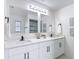 Bathroom with double sink vanity with white cabinets, quartz counters, and black hardware, with two mirrors at 12083 Rockford St, Spring Hill, FL 34608