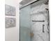 Close-up of the renovated bathroom shower featuring marble-style tile and a frameless glass door at 12083 Rockford St, Spring Hill, FL 34608