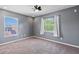 Bedroom with grey walls, plush carpet, ceiling fan and windows overlooking a tree-lined street at 12215 Adventure Dr, Riverview, FL 33579