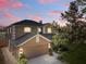 Beautiful two-story home with a two-car garage and well-manicured landscaping at dusk at 12215 Adventure Dr, Riverview, FL 33579