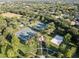 Aerial view of community tennis and volleyball courts, and a park with mature trees at 12215 Adventure Dr, Riverview, FL 33579